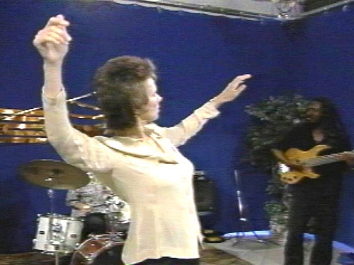Dr. Nancy Mroczek performing with a guy on her right on the guitar.