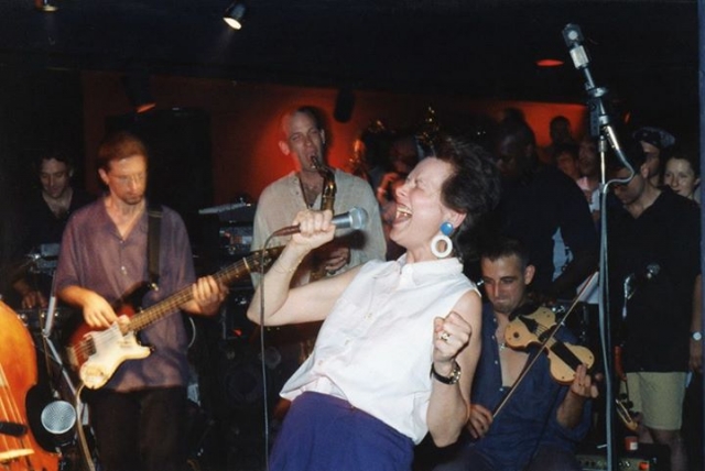 Dr. Nancy Mroczek with the band and audience behind her.